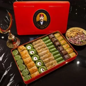 Red Metal Hafız Mustafa box with 8 different pistachio baklava flanked a plate of Gaziantep pistachios and an copper coloured Ottoman half moon.