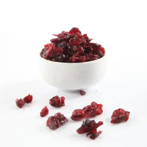 Cranberries in a white bowl surrounded by sprinkled cranberries