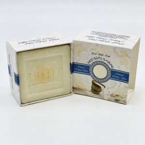 Open beige, golden box with blue line showing a square white bar of Organic Goat Milk Soap.