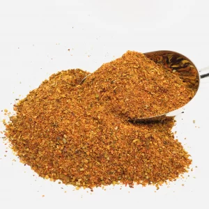 Pile of BBQ (Ottoman) Spice Mix with a large metal spice spoon on a white background.