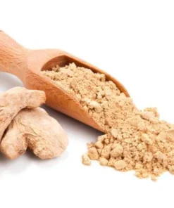 A wooden spice spoon overflowing with Ground Ginger. Flanked by two Dried Ginger Roots