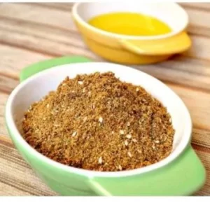 White and green bowl with spice mix of zaatar dukkah and yellow bowl with olive oil in the background