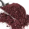 Silver coloured scoop with a pile of purple sumac spice on a bed of more sumac spice